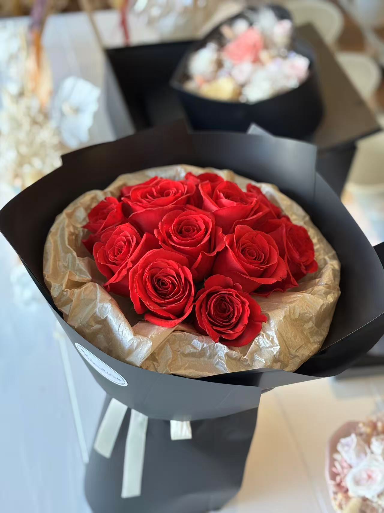 11 Red roses in black round packaging