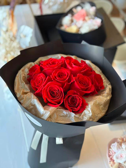 11 Red roses in black round packaging